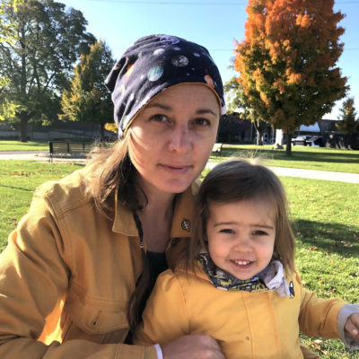 woman holding child in sunny outdoor park